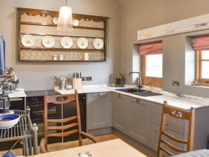 BodiamThe Hen House的厨房配有水槽和带椅子的柜台。