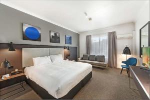 悉尼CKS Sydney Airport Hotel的酒店客房设有一张大床和一张沙发。