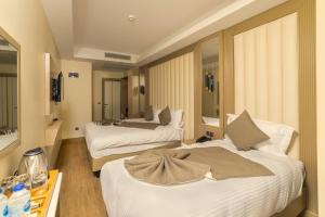 伊斯坦布尔Asilzade Hotel Sirkeci的客房设有两张床和一张带瓶装水的桌子。