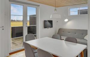 博托比2 Bedroom Beautiful Apartment In Vggerlse的一间配备有白色桌椅和电视的用餐室