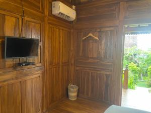 珀尼达岛Kepaon Gari Inn的客厅设有木墙和平面电视。