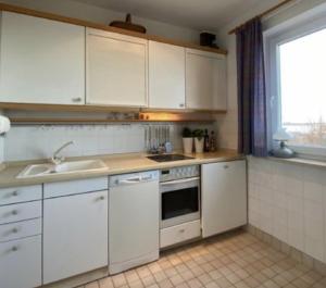 维滕Haus Seelöwe Wohnung 1的厨房配有白色橱柜、水槽和窗户。