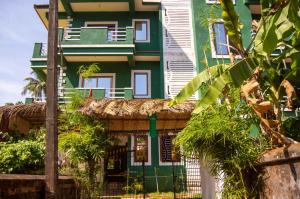 阿伯来Green Nest Hostel, Baga - Arpora的前面有栅栏的绿色白色房子