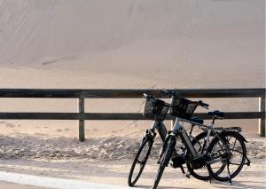 雷讷瑟Camping Hotel Renesse的停在沙子围栏旁的自行车