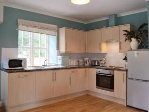 BelladrumThe Kennels Bothy - Beaufort Estate的厨房配有木制橱柜和白色冰箱。