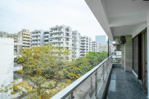 古尔冈FlxHo Uno - Serviced Apartment & Rooms - Golf Course Road的树木和建筑的建筑的阳台