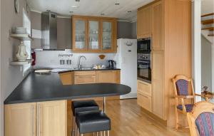 法尔松Nice Home In Farsund With Kitchen的厨房配有木制橱柜和黑色台面