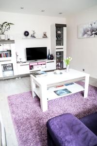 利耶帕亚Magnolia apartment的客厅配有白色桌子和紫色地毯。