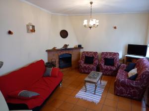 RabalCasa da Ribeira em Rabal的客厅配有红色的沙发、椅子和壁炉