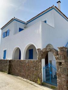 爱琴娜岛Psamathe Aegina Apartments的白色的房子,有蓝色的大门和石墙