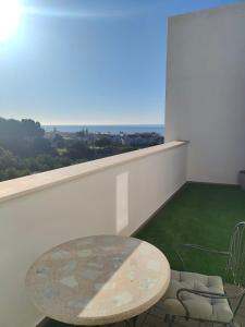 托雷德本纳贾尔邦Atico con piscina, golf, vistas al mar的阳台配有桌子,享有海景。