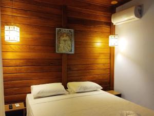 贝洛奥里藏特VIA SPE - Pousada的一间卧室设有木墙和一张铺有白色床单的床。