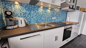 巴特萨尔茨乌夫伦Appartement Vanille, Ferienwohnung mit eigenem Eingang, wie ein kleines Haus的厨房设有水槽和蓝色瓷砖墙。
