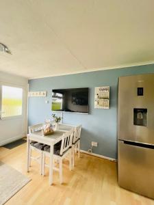 Brading“SEA HEAVEN “ chalet in Sandown Bay Holiday Park的厨房配有白色的桌子和冰箱。