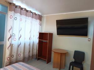 阿亚库乔HOSPEDAJE SAMAY WASI (AYACUCHO)的一间卧室配有一张床、一台电视和一把椅子