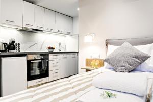 科孚镇Ionian Citizen Atelier的一间卧室配有一张床,厨房配有白色橱柜