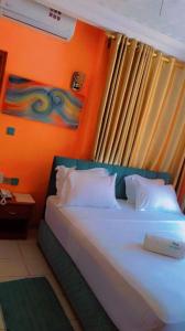 科托努HÔTEL NOAHGARDEN 2的一间卧室配有一张橙色墙壁的床