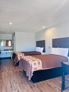 LulingCoachway Inn的酒店客房带两张床和一张桌子以及椅子。