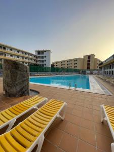 圣巴托洛梅Apartment Modern 2 Playa del Ingles的一座游泳池,里面设有两个黄色长椅