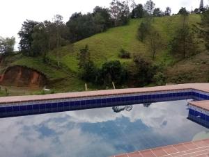 El PeñolEcoGranjasYa的水面上反射天空的游泳池