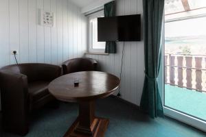 乌斯拉尔浪漫之旅酒店的配有桌子、椅子和电视的房间