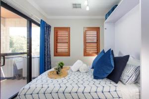 珀斯Bambino 438的一间卧室配有一张带蓝色枕头的床和一张桌子。