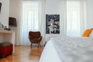 的里雅斯特ViandanteHome, Luxury Rooms的一间卧室配有一张床、一把椅子和窗户。
