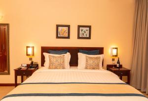 达累斯萨拉姆白沙度假酒店及会议中心的一间卧室配有一张大床、两张桌子和两盏灯。