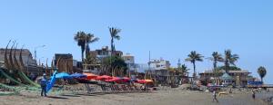 特鲁希略Bellos Dptos Huanchaco, Perú a 50 metros del mar的海滩上有人和遮阳伞海滩