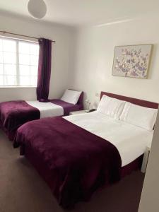 North Cornelly格林阿里克汽车酒店的两张位于酒店客房的床铺,配有紫色床单