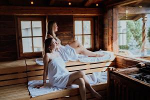 菲根黑尔德运动疗养四星级酒店的两名女性坐在桑拿浴室的床上