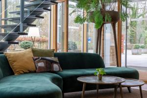 乌得勒支米特兰德酒店的客厅配有一张绿色沙发,设有一张桌子