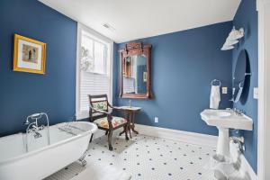 温斯顿·塞勒姆Summit Street Inns的一间带蓝色墙壁、浴缸和椅子的浴室