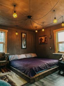 塔尔西Private Farm Jakuzzi Sauna in the forest的一间卧室配有一张带紫色床单和灯的床