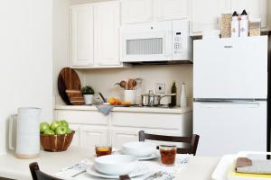 莫比尔InTown Suites Extended Stay Mobile- South Beltine的厨房配有白色橱柜和一张带食物的桌子。