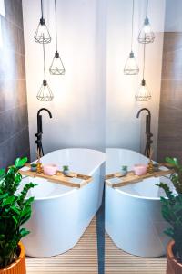 克卢日-纳波卡Thome Ego Flat的浴室设有2个白色浴缸,配有盆栽植物