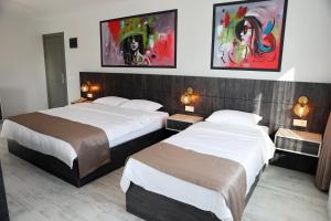 埃迪尔内SAR-PER Hotel的两张床铺,位于酒店客房,墙上挂有绘画作品