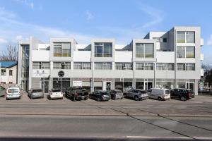 塞尔福斯贝拉公寓及客房的一座白色的大建筑,汽车停在停车场