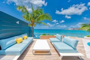 马霍礁Surfsong Villa- Luxury Water Front Villa for 12的一个带蓝色沙发、棕榈树和大海的庭院
