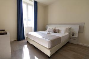 马瑞纳迪卡拉拉Doride Suites Boutique Hotel的一间卧室配有白色的床、蓝色窗帘和窗户