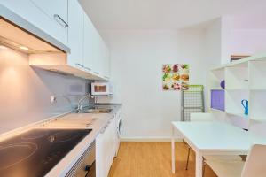 巴达洛纳Precioso Loft en Badalona Centro的厨房配有白色橱柜、水槽和桌子