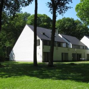 胡塔伦De Bosdreef - Hengelhoef - duplex met verwarmd openluchtzwembad的一座白色的大建筑,在草地上种有树木