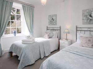 邓斯特Dunster Mill House的一间白色卧室,配有两张床和窗户