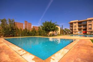 马拉喀什Appartement luxueux Coralia avec piscine的大楼前的蓝色海水大型游泳池