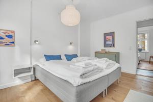 哥本哈根NABO Hotel Apartments的白色卧室配有一张带蓝色枕头的大床