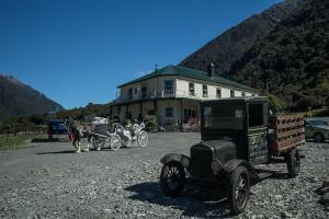 Otira奥蒂拉驿站酒店的一辆旧车和一辆马车在房子前面
