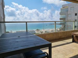 阿卡Beachfront Gallery的阳台配有桌子,享有海滩美景