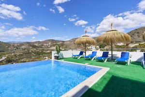阿尔姆尼卡Villa Joya del Mediterraneo的一个带蓝色椅子和遮阳伞的游泳池