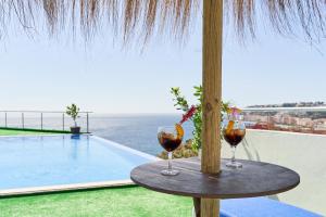 阿尔姆尼卡Villa Joya del Mediterraneo的两杯酒坐在游泳池旁的桌子上
