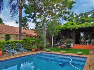 比勒陀利亚Ambiance Guesthouse的一个带椅子的庭院和房子的游泳池